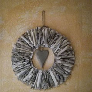 Treibholz Kranz in weiß-grau mit grauem Herz, an cremefarbener Wand.
