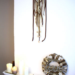Holzkranz mit Kerzen und einem Wandhänger aus Filzbändern.