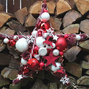 Weiß-roter Stern mit eingearbeiteter Lichterkette an einen Holzstapel gehängt.