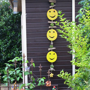 Dekokette mit drei gelben Smileys am Gartenhäuschen.