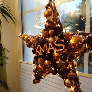 Stern in schwarz - kupfer - braun mit XMAS als stimmungsvolle Fensterdekoration für die Weihnachtszeit.