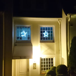 Sterne mit Lichterketten von außen fotografiert als leuchtende Fensterdekoration.
