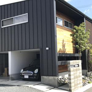 建築で元々備わっていたビルドインタイプのカーポート。外壁とコンクリート、砕石砂利によってグレー系でモノトーンな印象が落ち着きます。