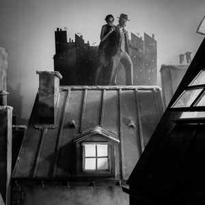 un couple dans un clip en noir et blanc qui marche sur des toits 