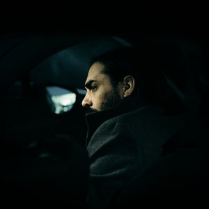 portrait couleur de l'artiste GRINGE dans une voiture dans une ambiance sombre et cinématographique