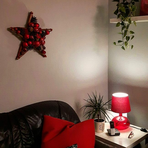 Weihnachtlicher Deko Stern in rot über der Couch im Wohnzimmer.