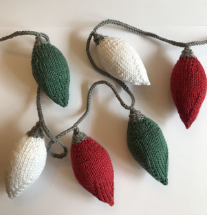 Gestrickte Lichterkette aus Glühbirnen in weiß, rot und grün.