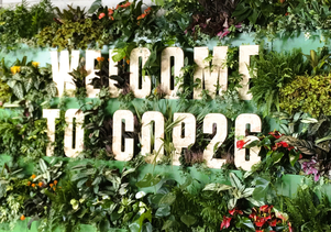 写真：COP26会場の植物装飾の壁に「WELCOME TO COP26」の英語サイン