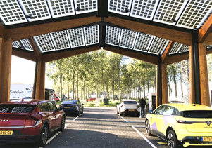 写真：ソーラーパネルで屋根が覆われた屋外駐車スペースの下に車が並ぶ風景