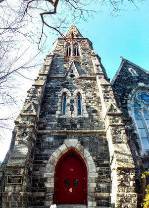 An old church in cambridge boston ma, old bricks and red door, sky and tree