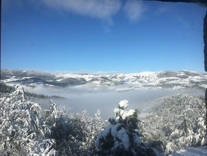 Une vallée montagnarde en ardéche enneigée avec un tapis de brouillard, vue de la terrasse du gite de la gorre à louer en ardeche