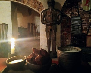 Plate of Latvian garlic rye bread with cream sauce and mug of beer with a candle and suit of armour in background at Lasite medieval restaurant in Old Riga