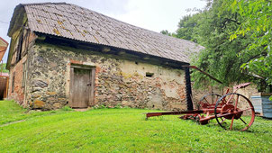 Old stone farm building with red antique plough in Striķi village near Saldus, Latvia