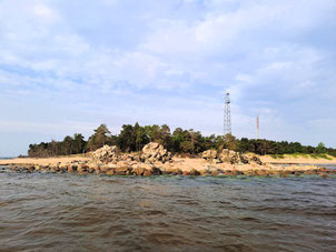 Cape Kolka in Kurzeme, Latvia, seen from the water, with trees and a radio mast in the background