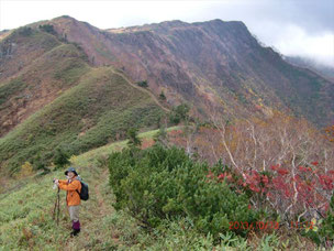 いくつものピークを通る登山道をバックに写真を撮る