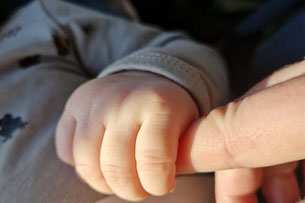 Babyhand hält meinen Finger