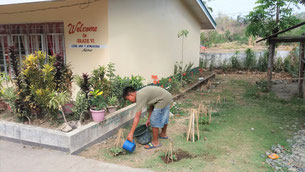 Children take turns watering the seedlings in the school ground.