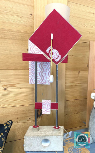 Lampe artisanale design à la structure verticale rouge avec béton, bois, laiton et tige métallique. Une création originale d'Isabelle Lachat Créations en Haute Savoie à proximité d'Annecy.