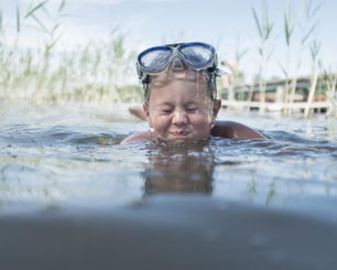 Kind beim Schwimmen im klaren Wasser des Hallstättersees im Salzkammergut