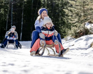 Familie beim Rodeln im winterlichen Salzkammergut