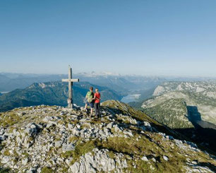 Wanderer am Gipfelkreuz mit Panoramablick über den Traunsee und die Bergwelt des Salzkammerguts