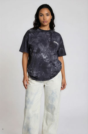 model wearing bleached out wide denim jeans with a batik print t-shirt in dark grey and black collar