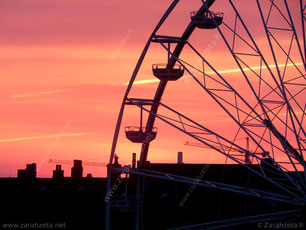Riesenrad vor Stadtsilhouette in der Morgenröte