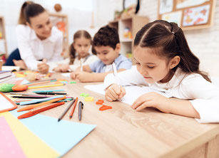 Kinder sitzen an einem Tisch und schreiben