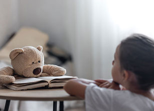 Ein Kind sitzt vor einem Teddybär