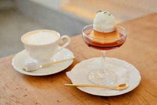 コーヒーの入ったカップ&ソーサ。ノート、鉢植えのグリーン。