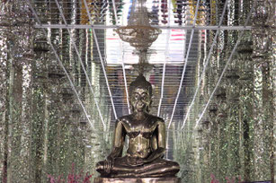 Un bouddha en argent assis dans une salle remplie de miroirs