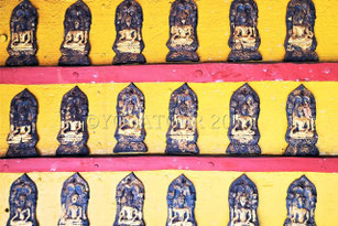 Amulettes dorées de Bouddha dans un temple rouge et jaune en Thaïlande