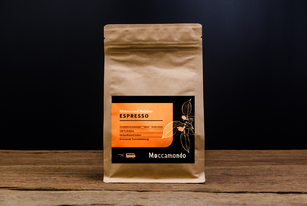 Eine 250 Gramm Packung Monsooned Malabar Espresso steht auf einem Holztisch.