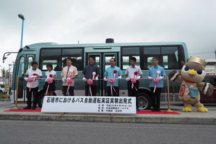 自動運転バス運行実験の出発式で記念撮影する関係者=25日午後、石垣港離島ターミナル