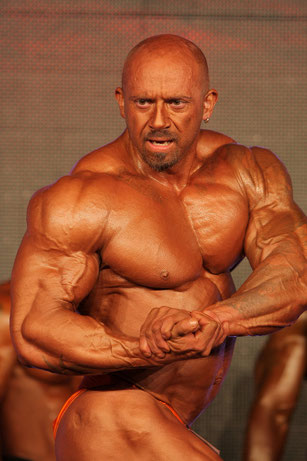 Bodybuilder mit abslout extremer Muskelmasse posiert