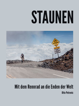 Das Cover von "Staunen" zeigt eine asphaltierte Straße inmitten von Geröll. Auf der Straße fährt ein Fahrradfahrer.