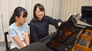 ピアノ講師が子供の生徒に楽譜の読み方を教える