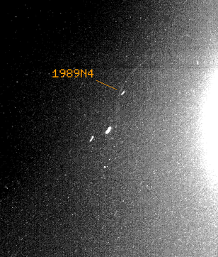 Galatea (1989N4) mit zwei anderen Neptunmonden und einem leichten Ringbogen im August 1989 von Voyager 2 aus 8,6 Millionen Kilometer Entfernung. Wegen einer längeren Belichtungszeit der Aufnahme sind sie langgezogen. Neptuns Schein ist links zu sehen.