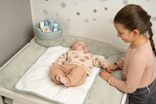 Schwester an der Wickelkommode & Baby liegend auf der Ersatz-Frottee-Auflage von der Be Be's Collection