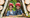 Zwei Kinder mit Helmen schauen aus einem Holzstapel-Versteck im CLIMB UP! - KIDS-Park