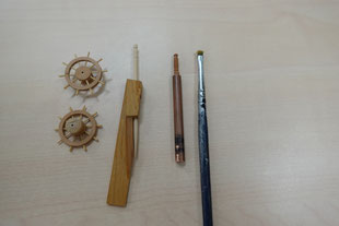 写真左側から順に　　　・舵輪の試作品・爪楊枝の先端加工治具・パイプ利用の角材保持具　・ドライブラシ用筆