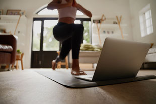Frau vor Laptop am Online-Yoga machen. Erhalte dein Feedback zu deiner Yoga Praxis durch Videoanalyse. 