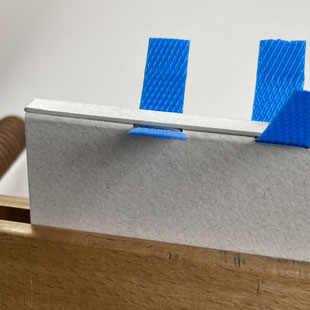 Coller sur le dos une bande de carton de la hauteur de la couverture et de la largeur du dos