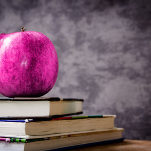 Lehrertisch mit Apfel und einem Bücherstapel