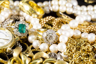 Eine Ansammlung verschiedener Perlen sowie Ketten, Uhren und Ringe aus Gold.