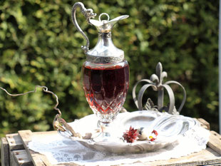 Heilwein In einer Glaskaraffe mit drachenförmigem Griff leuchtet eine rubinrote Flüssigkeit.