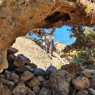 Eine Felsenlandschaft auf Kreta. Durch eine Öffnung im Stein ist im Hintergrund das Meer zu sehen.