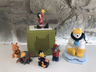 Foto einer Toniebox mit mehreren Tonie-Figuren und einem SAMI Lesebären