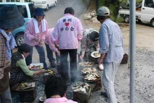 持参したコンロの上の焼き肉・野菜「うまそう！」自治会の鈴木さんのホタテは新鮮で「会員一同感激」