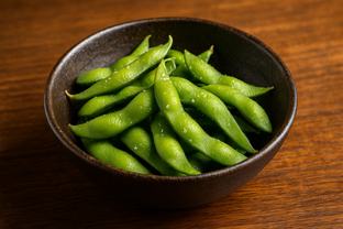 Fresh green edamame sprinkled with sea salt in a rustic Japanese bowl, wooden izakaya table background.